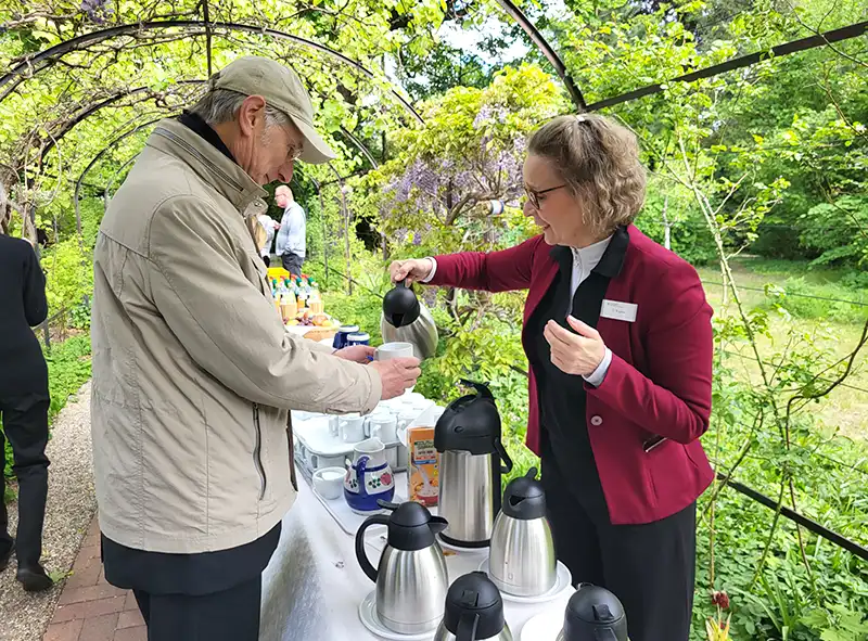 Eine ältere Frau schenkt einem älteren Mann einen Kaffee ein